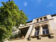 Schöne alte Fassade in Beige und Ocker mit Topfpflanzen auf dem Balkon in einer Allee vor blauem Himmel im Sommer bei Sonnenschein im Nordend von Frankfurt am Main in Hessen