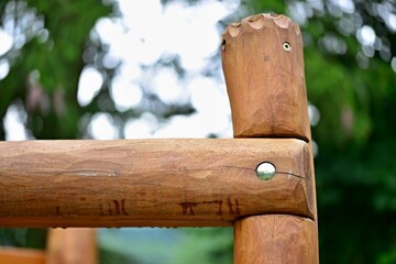 Detail of a wooden baby climbing frame. Two wooden poles connected by a steel screw. Hand decorated playground. Ready to play.