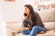 © Alvaro Montero/ADDICTIVE STOCK - Young female in casual outfit sitting on cozy couch and talking with friend on mobile phone while spending weekend at home
