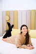 © Antonio Ovejero/ADDICTIVE STOCK - Charming female in oversize sweater and stockings lying on soft bed in modern bedroom and cheerfully looking at camera