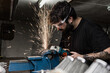 © Carlos Rodelas/ADDICTIVE STOCK - Side view of bearded male master wearing protective glasses standing in shabby workshop and cutting metal detail with grinder tool