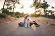© Gustavo Pozo/ADDICTIVE STOCK - Side view of serene girlfriend and boyfriend sitting back to back on roadway with Old English Sheepdog and enjoying amazing sunset in summer