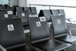 © Jake Jakab/ADDICTIVE STOCK - Rows of empty black seats in public waiting area for people with physical disabilities and people with special needs with square white sign demonstrating person on wheelchair