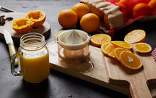 From Above Composition Of Halves Of Fresh Oranges On Wooden Boards And Mesh Bag Near Glass Jar With Orange Custard And Plastic Squeezer