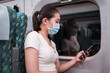 © Juan Alberto Ruiz/ADDICTIVE STOCK - Side view slim young Asain lady traveling by train browsing modern cellphone while sitting on comfortable passenger seat near window and suitcase during coronavirus epidemic