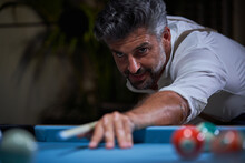 Confident Focused Gray Haired Male In White Shirt Preparing For Shot With Cue While Playing Billiards Game