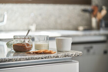 Glass Of Milk And Jar Of Brown Sugar Placed On Counter With Cup Of Coffee And Cookies In Modern Kitchen