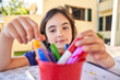 © Philippe Degroote/ADDICTIVE STOCK - Positive school aged girl while sitting at table and choose drawing with colorful pencils in copybook during free time
