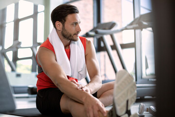 Pensive athlete warming up for sports training in a health club.