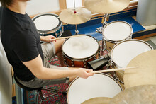 From Above Cropped Unrecognizable Casual Male Drummer Playing On Drum Kit Sitting On White Background Stage