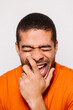 © Victor Torres/ADDICTIVE STOCK - Cheerful man isolated on white background. He is wearing an orange t-shirt and laughing with eyes closed