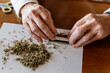 © Westend61 - Close-up of retired senior man rolling weed on table