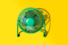 Green Electric Fan Against Yellow Background