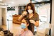 © Westend61 - Female hairdresser with mask staining hair of female customer with mask