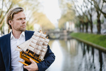 Businessman Holding Model Ship At A Channel