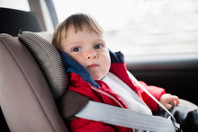 Close-up Of Cute Baby Boy Sitting On Car Seat
