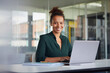 © Westend61 - Portrait of smiling businesswoman working on laptop at desk
