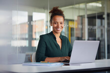 Portrait Of Smiling Businesswoman Working On Laptop At Desk