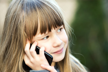 Portrait of pretty child girl with long hair talking on cell phone. Little female kid communicating using smartphone. Children communication concept.