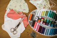 Close-up Of Sewing Items With Floral Protective Masks On Table At Home