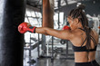 © Westend61 - Female athlete wearing red gloves practicing boxing drill on punching bag in gym