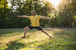 © Westend61 - Man practicing warrior 2 position on grass against trees at park