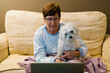 © Westend61 - Ill senior woman sitting with dog while discussing over video call through laptop at home