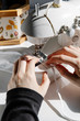 © Cavan Images - Unrecognizable craftswoman stitching piece of fabric while working in workshop and creating fabric masks