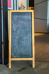 Wall Mural - Wooden rustic blackboard in front of restaurant entrance. Mock up Menu Blank Blackboard sign stand Shop Cafe Restaurant. Street Magnetic Sidewalk Chalkboard.