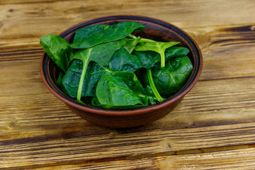 Poster - Fresh green spinach leaves in bowl on a wooden table