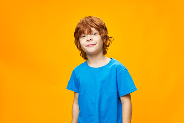 boy red hair blue t-shirt yellow isolated background freckles and a beautiful smile of a child's loo