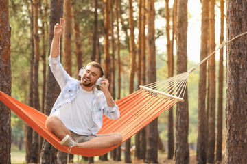 Canvas Print - Young man listening to music while relaxing in hammock outdoors