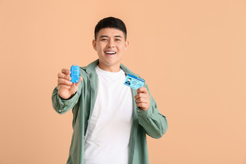 Poster - Happy Asian man with car key and driving license on color background