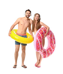 Poster - Young couple with headphones and inflatable rings on white background