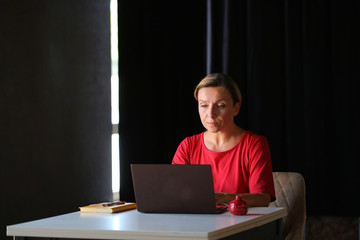 a woman in a red dress is working on a laptop at home in a dark room