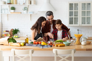 Happy parents teaching son chopping vegetables