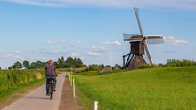 Tourist Passing Windmill The Monnikenburenmolen Or Nijhuizumermolen A Drainage Mill In Nijhuizum, Friesland, Netherlands.