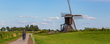 Tourist Passing Windmill The Monnikenburenmolen Or Nijhuizumermolen A Drainage Mill In Nijhuizum, Friesland, Netherlands.