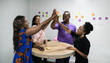 © JonoErasmus - Diverse businesspeople laughing and high-fiving after an office teamwork meeting