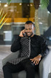 © JonoErasmus - Smiling young North African businessman talking on his cellphone at work space