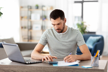 Canvas Print - remote job and business concept - man with papers, calculator and laptop computer working at home office