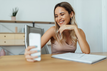 Wall Mural - Close-up portrait of a beautiful happy young woman using smart phone.