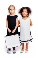 Wall Mural - Little fashionable girls girlfriends of two different nationalities posing on a white background with shopping bags