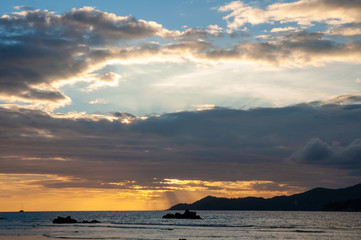 Beautiful tropical sunset with vibrant warm colours over the water with the silhouette of an island