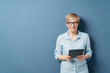 © contrastwerkstatt - Smiling woman with tablet against blue background