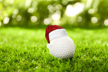 Wall Mural - Golf ball with small Santa hat on green course