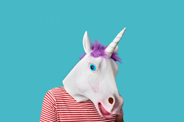 Wall Mural - man wearing a unicorn mask on a blue background