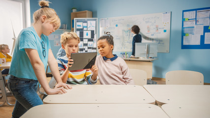 Wall Mural - Elementary School Computer Science Class: Two Girls and Boy Use Digital Tablet Computer with Augmented Reality Software, They’re Excited, Full of Wonder, Curiosity. Children in STEM, Playing, Learning