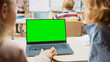 © Gorodenkoff - Elementary School Science Class: Over the Shoulder Little Boy and Girl Use Laptop with Green Screen Mock-up Template on a Display. Physics Teacher Explains Lesson to a Diverse Class full of Smart Kids