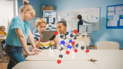 Wall Mural - three diverse school children in chemistry science class use digital tablet computer with augmented 
